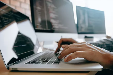 Software developer writing code on a laptop